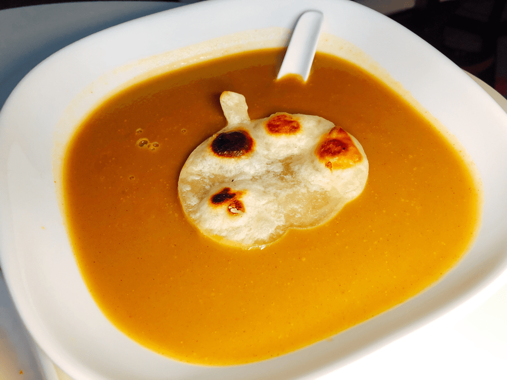 Bowl of Butternut squash soup with a pumpkin shaped tortilla bread on top