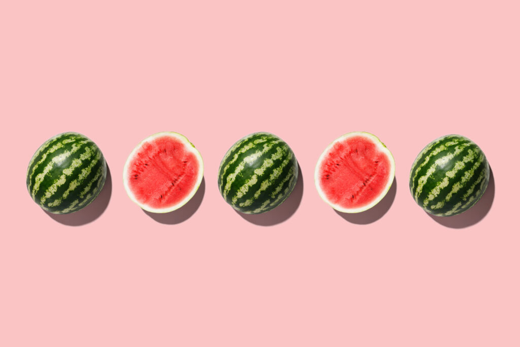 Row of fresh watermelon in center on pink backgrond. Top view. Top view. 