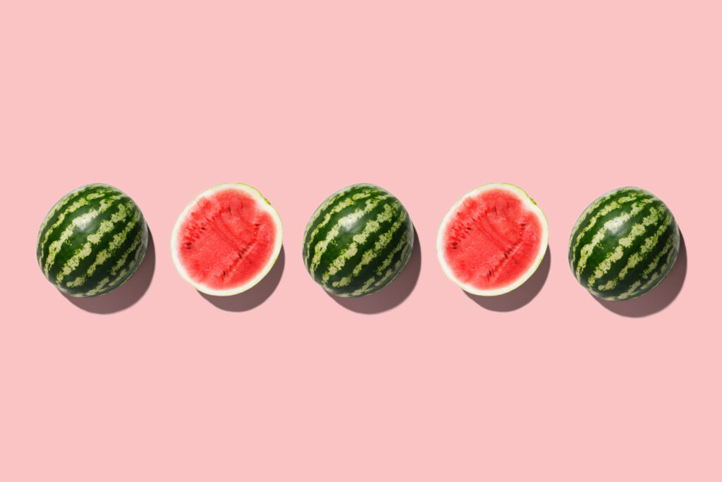 Row of fresh watermelon in center on pink backgrond. Top view. Top view.