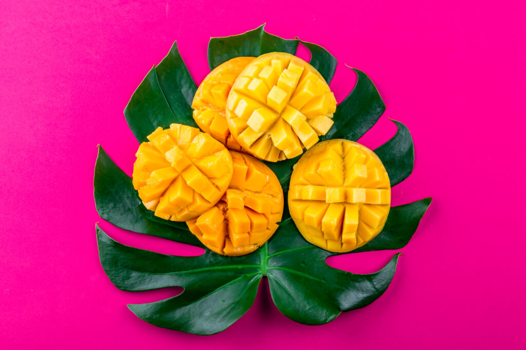  mango and tropical leaves on turquoise background. Flat lay. Food concept. Tropical concept.